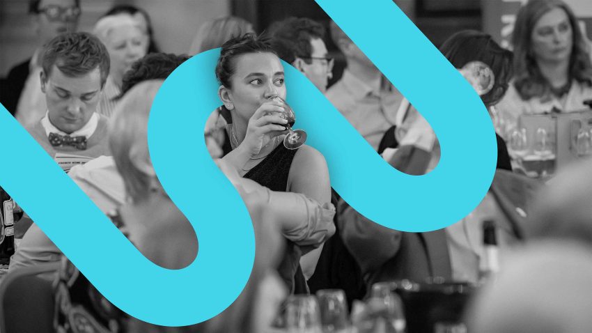 A black and white image of a woman drinking a glass of wine with a blue graphic swirling around her.