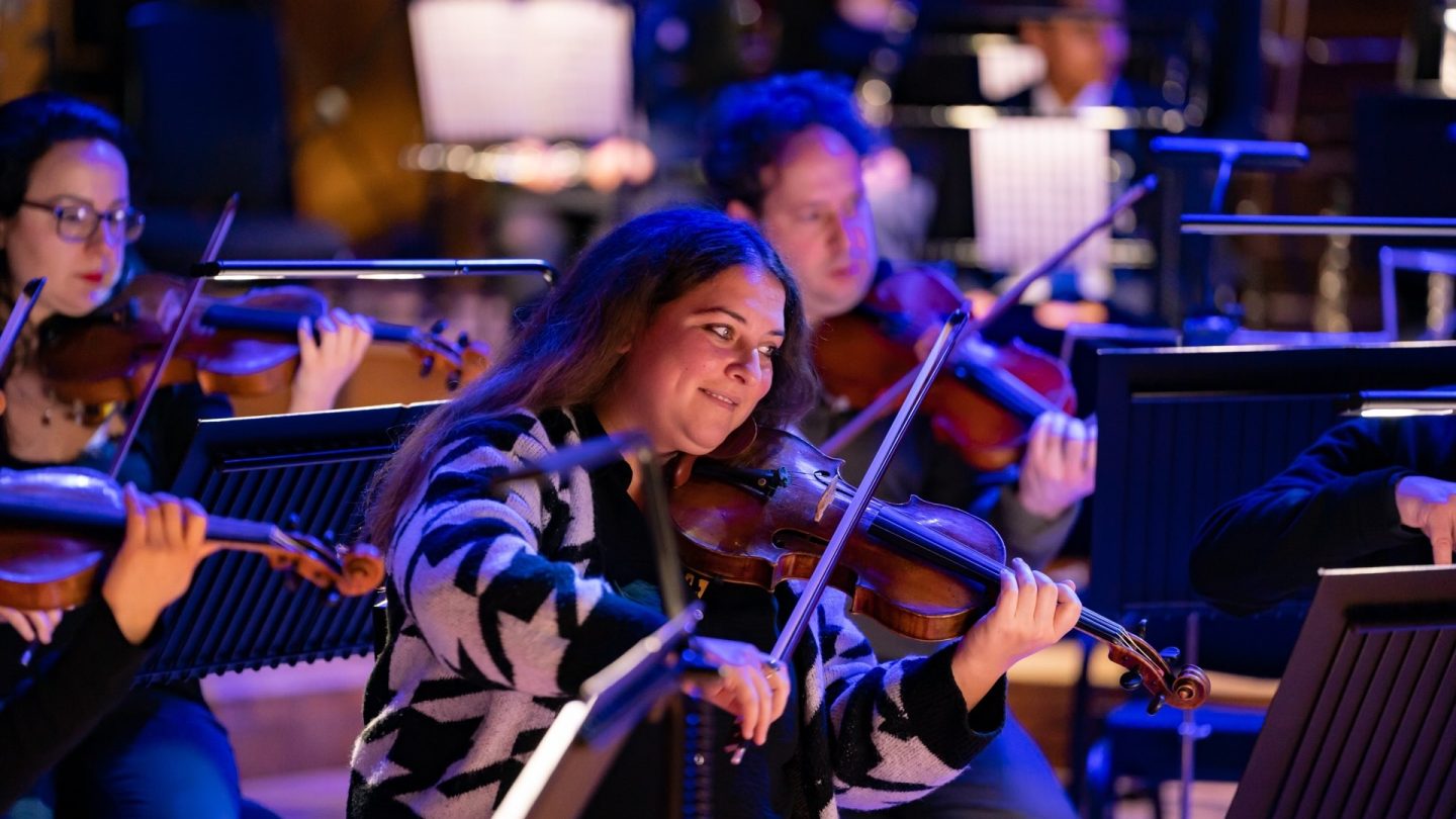 Smiling woman plays the violin.