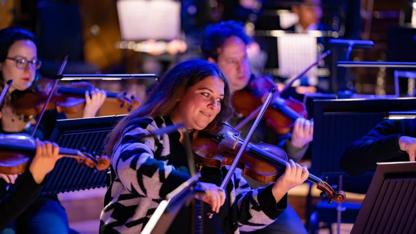 Smiling woman plays the violin.