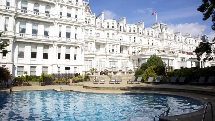 A grand white building behind a blue swimming pool.