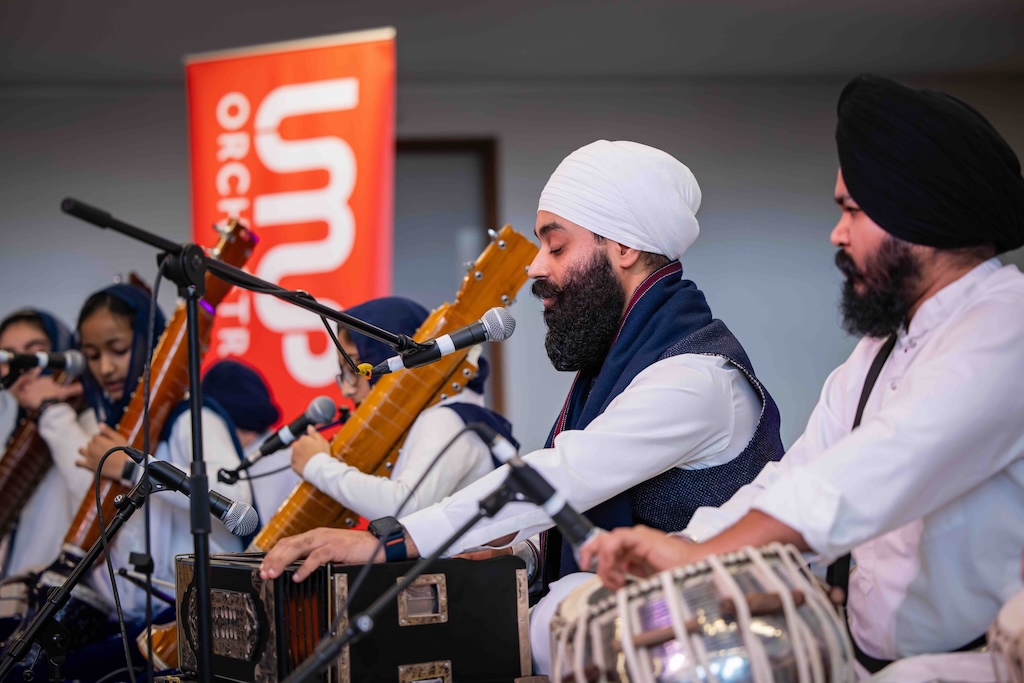 Two men in turbans perform on south Asian instruments.
