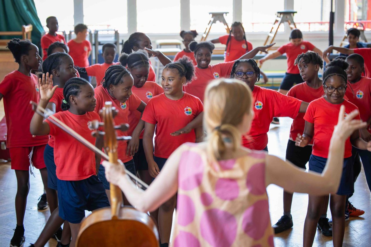 Children dance in front of a cellist.