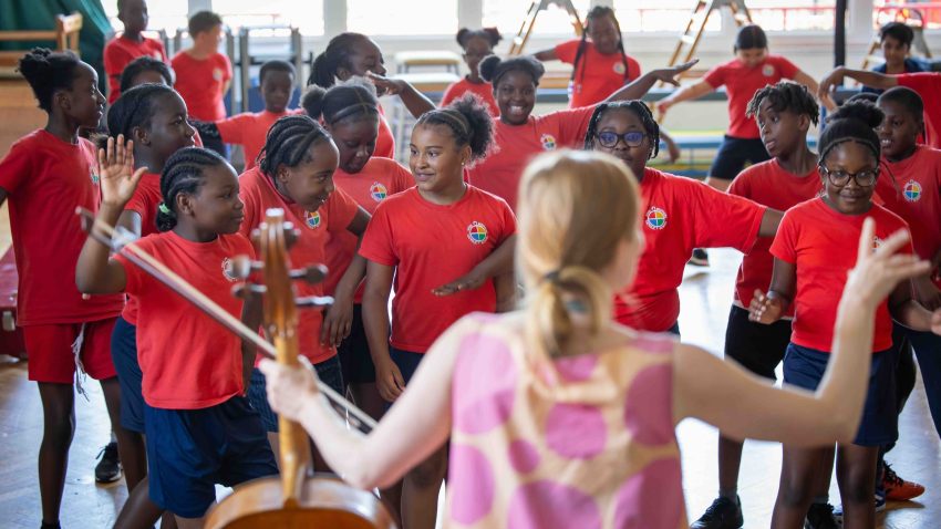 Children dance in front of a cellist.