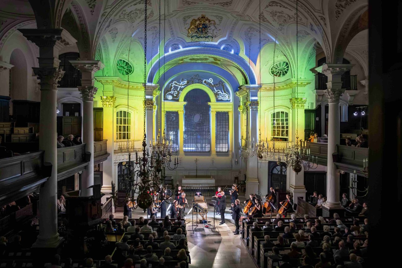 Beautiful patterns are projected on the back wall of a church, over the heads of musicians.