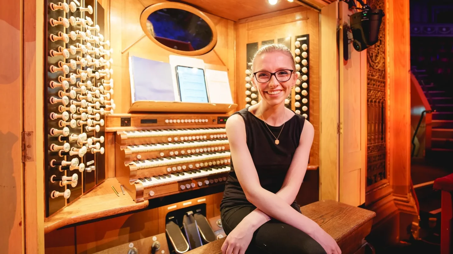 Smiling woman sits in front of an organ console.