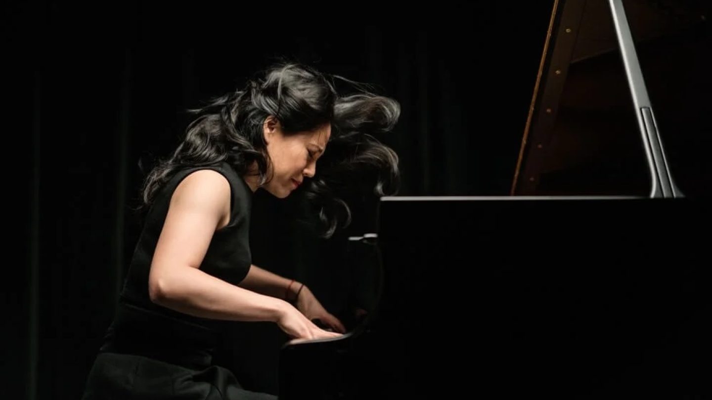 A woman dramatically plays the piano.