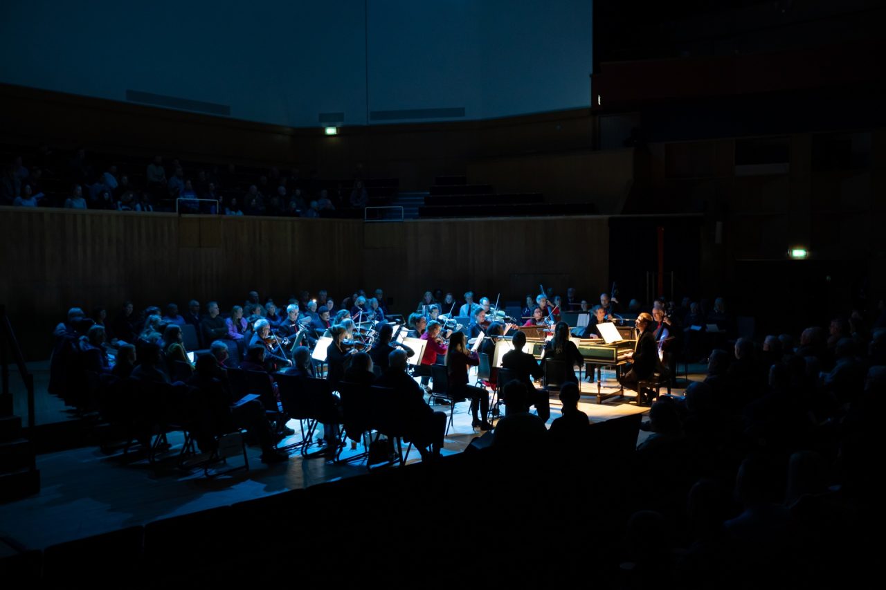 Atmospheric lighting surrounds an orchestra as they play.