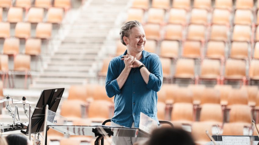 Jonathan smiles in from of concert hall seating.