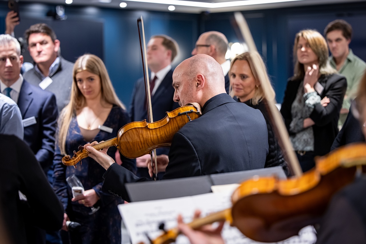 Man plays the violin surrounded by a crowd.