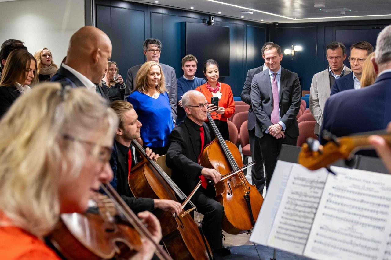 A crowd surrounds musicians playing the cello.