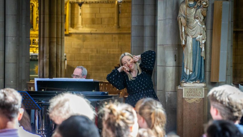 A woman in a spotty top playfully holds her hands to her face to mimic an animal.