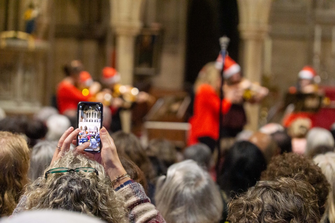 An audience member holds their phone up to take a photo.