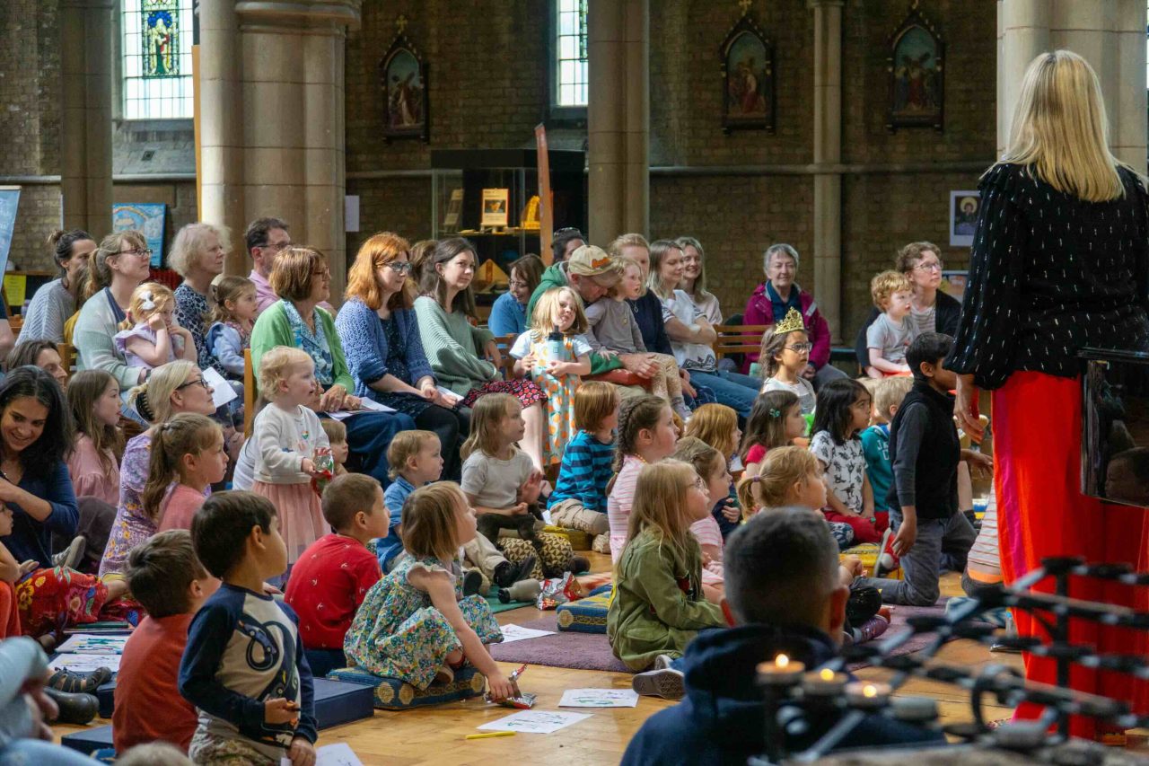 crowd of children and their parents sit in a church.