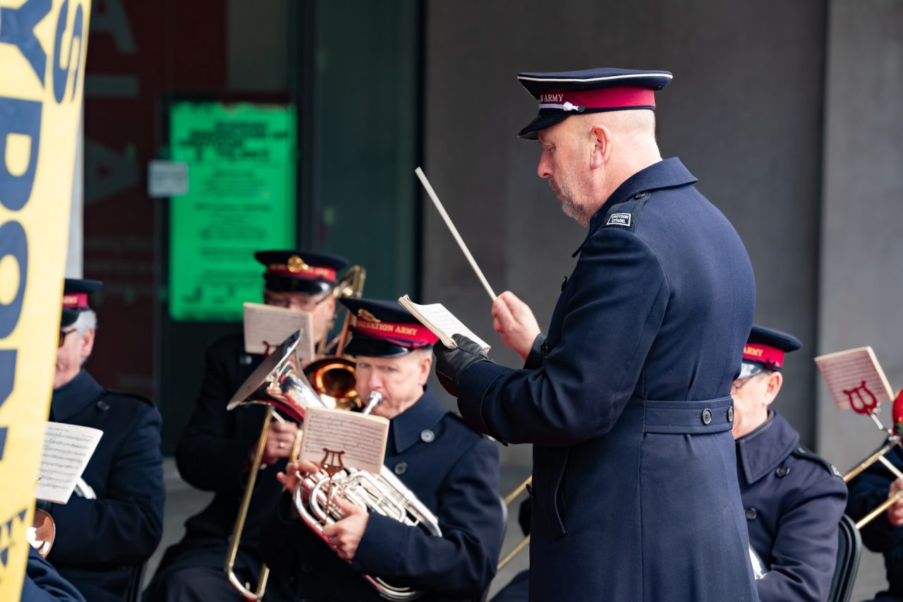 A conductor from the Salvation Army stands in front of the band.