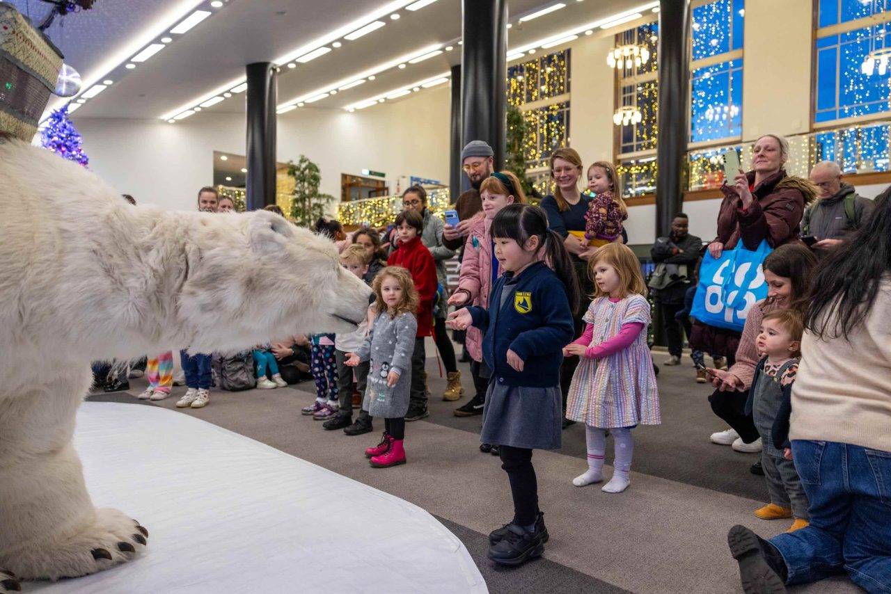 A young girl reaches out to an animatronic polar bear.