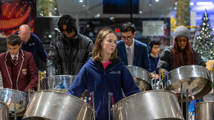 A young girl plays two steel pans.
