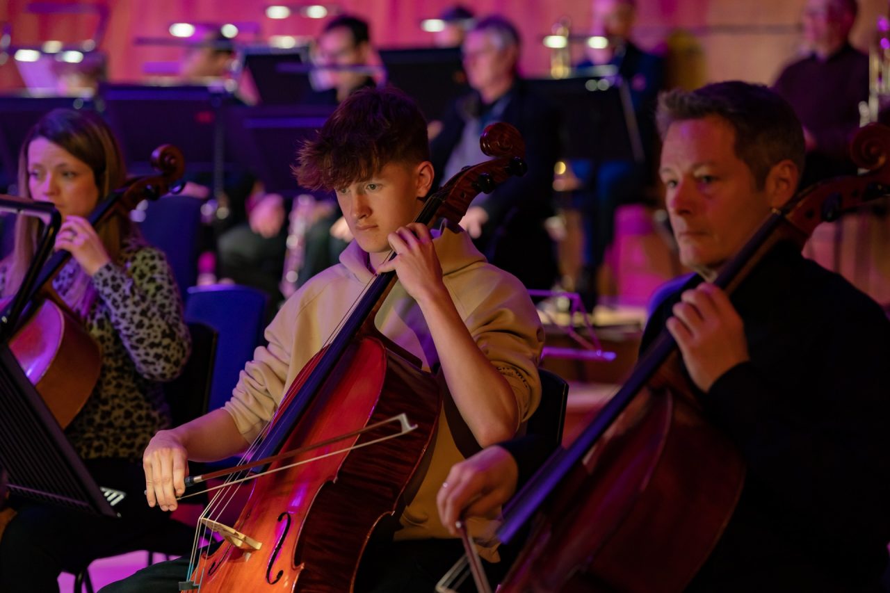 Two men play the cello.